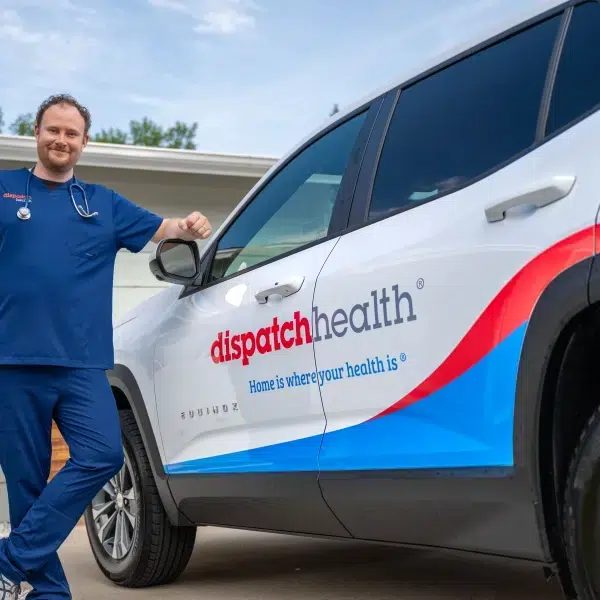 DispatchHealth medical professional standing beside branded mobile medical vehicle