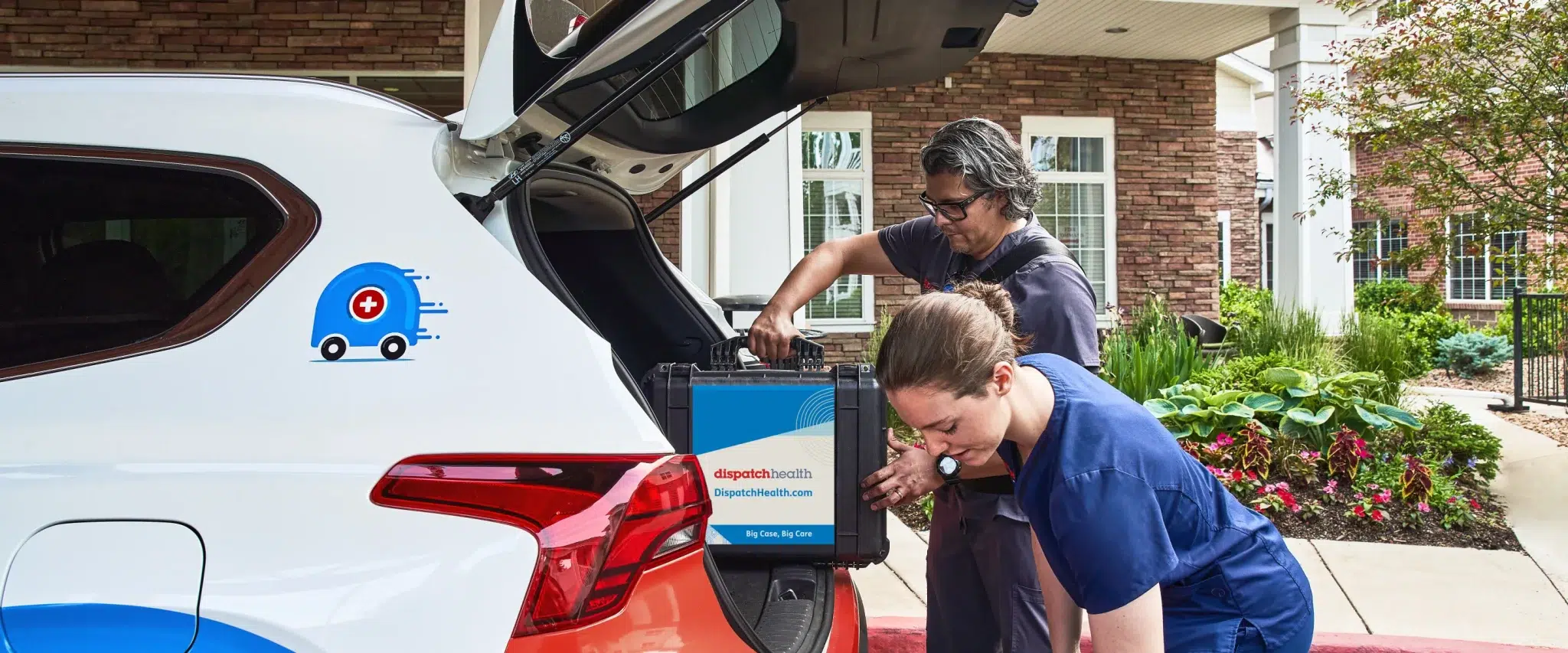 Two DispatchHealth medical professionals loading equipment into branded SUV outside residential building