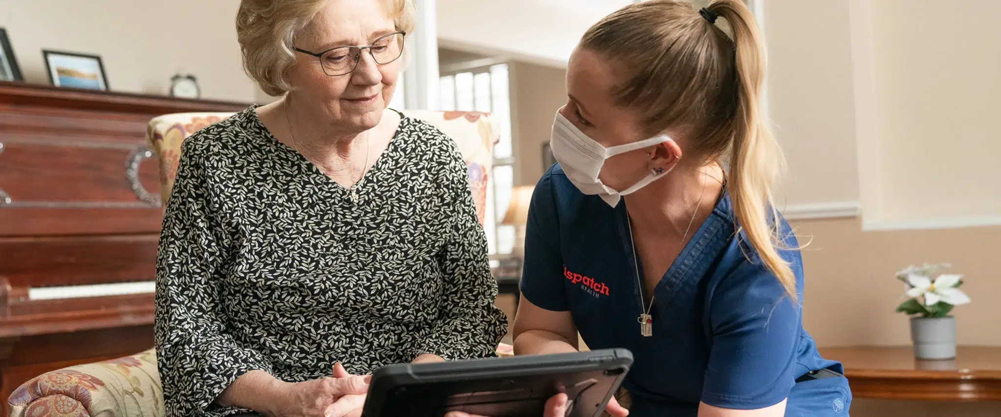 DispatchHealth provider using an iPad to guide an elderly patient in understanding medical instructions.